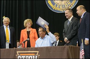 Gov. John Kasich, center, performs a ceremonial signing of House Bill 484  with state and local officials, from left, former Bowling Green State University trustee J. Robert Sebo, BGSU President Mary Ellen Mazey, state Rep. Tim Brown (R., Bowling Green), and state Rep. Cliff Rosenberger (R., Clarksville, Ohio). The law, officially signed last week, changes the state funding formula for two-year colleges to a performance-based model similar to one passed for four-year schools last year.