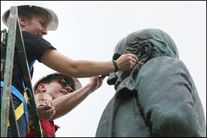 Hannah Yeager, left, and Conor Roberts apply wax after heating the statue of President William McKinley while they work with classmates to restore the sculpture, which is on the south side of the Lucas County Courthouse.