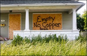 Writing on a boarded-up house at 2314 N. Erie St in North Toledo informs would-be intruders that valuable materials already have been stripped from the structure.