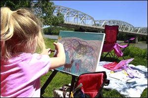 Callie Elder, 4, creates a colorful sky in her painting near the Maumee River during the open air art festival.