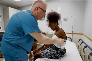 Kevin Cischke is a nursing student at Mercy College of Ohio who is doing an externship at Mercy St. Vincent Medical Center's emergency room. He takes the blood pressure of Kalyn Hodge, 15, of California, who was being seen for an ankle injury.