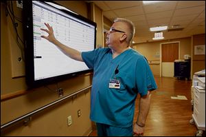 Kevin Cischke examines the board that announces where patients are located in order to see if a new patient has come into the emergency room.