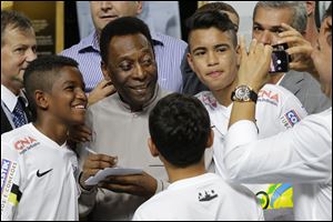 Soccer great, Pele pose for a photo next to young players of the Santos soccer team today during the inauguration of the Pele Museum in Santos, Brazil.