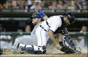 Kansas City Royals' Alex Gordon slides safely into home plate as Detroit Tigers catcher Alex Avila can't handle the throw on a error by pitcher Evan Reed in the seventh inning.