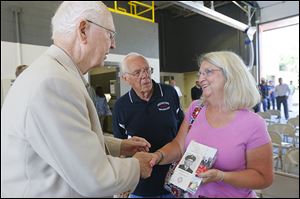Yvonne Juhasz, right, holds a picture of her father, William Kertesz, who was a Toledo firefighter in Station 3 while she shakes hands with former fire chief Carl Neeb, left. Former firefighter John Repp, center, looks on as they discuss the station on Monday.