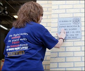 Gale Dickman, Jamie Dickman's aunt, touches the memorial plaque that firefighters at Station 3 will see each time they return from a run. The station has other reminders of the fallen firefighters.
