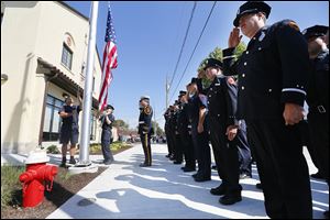 Jeff Koenigseker, center, a firefighter and honor guard commander, joins members of Toledo Fire and Rescue in saluting the flag during the reopening of Station 3, which closed in 2012. Pvts. Jamie Dickman and Stephen Machcinski, who died in the line of duty in January, belonged to Station 3.