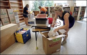 Ann Miller, foreground, a second-grade teacher, packs boxes for her classroom’s move from Old Fort to Bettsville. She is assisted by  third-grade teacher Kim Warren, back left,  and first-grade teacher Melissa Reineck. With the districts’ merger, the Bettsville building will house elementary students.