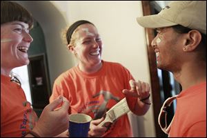 Fuller Center Bike Adventure’s Leah Spurlin, left, and Jenny Zeroun laugh after painting Kert Emperado’s face during a break at the home of Leroy and Dee Jones at 2038 Parkside Blvd. in Toledo.