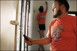 Kristina Bergstom and Greg Zeroun paint walls at the Toledo home of Roy and Dee Jones. The Fuller Center Bike Adventure cyclists travel an average of about 76 miles per day.