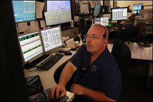 Lucas County EMS dispatcher Richie Etts, left, works on a computer as Bob Wilt, right, takes a call at the Lucas County 911 Dispatch Center on Monroe Street in Toledo on Friday.