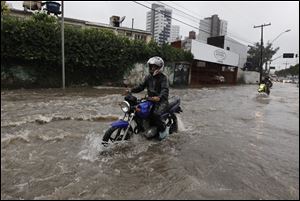 Motorcyclists make their way down a flooded street after heavy rain storms in Recife, Brazil, today.