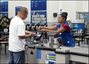 Conquisia Tyler, right, gives change to a customer at Sam's Club in Bentonville, Ark. Consumer spending rose just 0.2 percent last month after no gain in April.