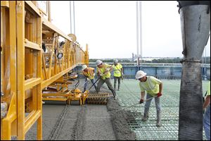 Tony Ortiz, Matt O’Neil, Jeff Mansfield, and Jeff Winters, from left, work with the concrete that will be the driving surface of the Anthony Wayne Bridge.