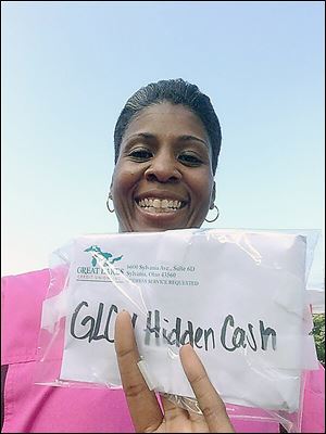 In this photo taken from Twitter, Erica Banks shows her winnings of the Hidden Cash scavenger hunt sponsored by the Great Lakes Credit Union. Ms. Banks tweeted a photo at 5:50 a.m. Thursday after she made her find near the Toledo Museum of Art.