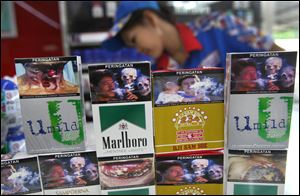 New packs of cigarettes displaying pictorial health warnings are arranged on the counter by a shop attendant for photographers at a convenience store in Jakarta, Indonesia.