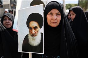 An Iraqi woman living in Iran holds a poster of the Grand Ayatollah Ali al-Sistani, Iraq's top Shiite cleric, in a demonstration against Sunni militants of the al-Qaeda-inspired Islamic State of Iraq and the Levant, and to support Ayatollah al-Sistani, in Tehran, Iran. 