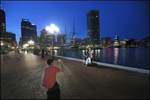 Niklas Rahkonen, who is in town for business from Los Angeles, takes a photograph of his wife, Dharma, and his 7-year-old son Eilan in front of the water in the highly visited Inner Harbor  area of Baltimore.