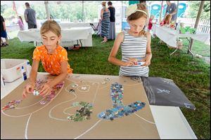 Lucy Wiltsie, 7, left, and Lilly Smith, 9, both of Delphos, Ohio, add puzzle pieces to a children’s art project in the Crosby Festival of the Arts Children’s Artistic Playhouse! sponsored by Mercy. Admission to the festival is free for children under 12.