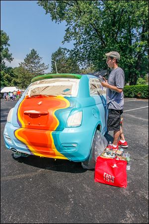 Har Simrit Singh of Toledo, an ‘‍aerosol graffiti artist,’ works on a Fiat 500. Work at the Crosby show include glass, graphics, painting, and photography.
