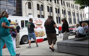 Customers wait by JoJo’s food truck on St. Clair Street downtown. Vendors pay $3 for each spot used by their truck or trailer.
