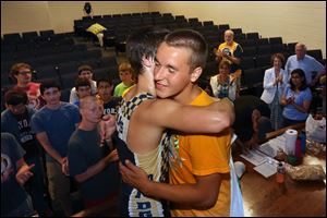 Bailey O'Brien, 18, center left, and James Miller, 17, center, right, embrace after the pair completed their world record rowing session Sunday at St. John's Jesuit Academy.
