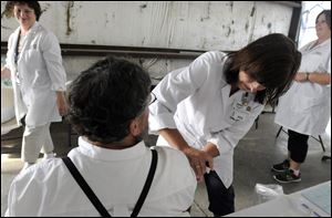 Richland Public Health nurse Renee Blankenship gives Daniel Martin, an Amish man from Holmes County his Measles, Mumps, & Rubella vaccination while he talks with nurses Sue McFarren, left, and Denise Close, right, at a clinic in Shiloh, Ohio. 