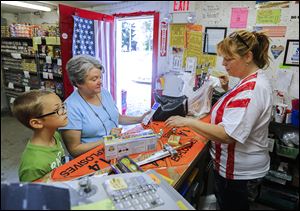 Kelli Miller, right, owner of   Lil John's Fireworks in Lambertville, helps Terry Vore and her grandson Bryce Boyd, 10, of Petersburg, Mich., check out after picking out fireworks for the holiday weekend.
