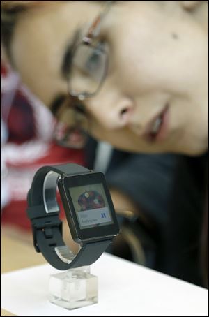 A woman looks at the LG G Watch, an Android Wear smart watch, on the demo floor at Google in San Francisco. The smart watch, which will be available soon, still is somewhat limited in what it can do, and even last year’s smart watches do some things that Android Wear software can’t.