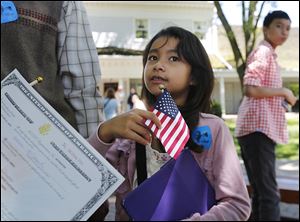 ‘‍Freedom, freedom, freedom,’ Sarah Xaiyarath, 7, of Northwood, answered for her mother, Martha Vieng Xaiyarath, about why she became a U.S. citizen. Mrs. Xaiyarath was one of 46 people from 29 countries to take the oath at Sauder Village in Archbold, Ohio.