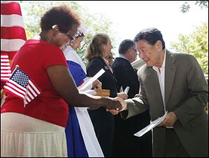 Johnny Taylor, left, of the League of Women Voters, gives new citizen Yan Namsrai, formerly of Mongolia, information on voting. U.S. District Judge James R. Knepp II presided over the ceremony on Friday.