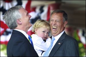Congressman Bob Latta, left, laughs at a joke from Michael Oxley, right as he holds his grandson Max Oxley, 2, at the dedication of the Michael G. Oxley Government Center at the Hancock Historical Museum in Findlay on Monday.