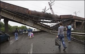 People walk under a destroyed railroad bridge over a main road leading into the east Ukraine city of Donetsk today.
