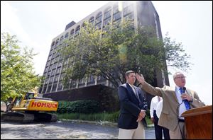 Mayor D. Michael Collins, in front of the former Clarion Hotel, calls the start of its razing an important step to remove blight. Councilman Matt Cherry, left, stands nearby. The hotel has stood empty since 2009 and has since caught fire and been vandalized.