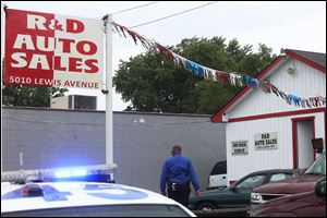 Law enforcement officials investigate the scene of a shooting and possible robbery  at R&D Auto Sales in West Toledo.
