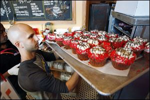 Crumbs Bake Shop managing partner Harley Bauer carries of tray of cupcakes during the store's grand opening in Beverly Hills, Calif. Crumbs on Monday, said it is shuttering all its stores, a week after the struggling cupcake shop operator was delisted from the Nasdaq.