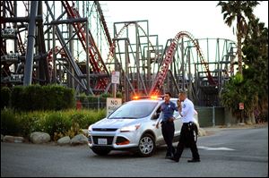 Members of the Six Flags Magic Mountain amusement park security staff monitor the situation at the exit of the park after riders were injured on the Ninja coaster Monday in Valencia, Calif.