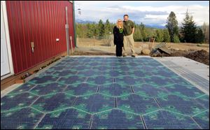 Scott and Julie Brusaw stand for a photo on a prototype solar-panel parking area at their company's business in Sandpoint, Idaho.