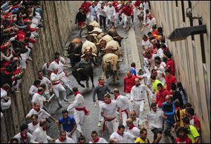 Revelers run ahead of ''FuenteYmbro'' fighting bulls on the way from Santo Domingo street to the bull ring during the running of the bulls Saturday at the San Fermin festival, in Pamplona, Spain.