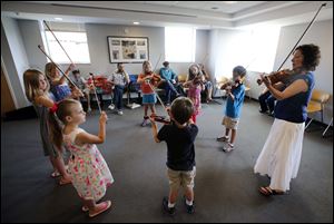 Cheryl Trace, right,  of the Toledo Symphony teaches children how to play the violin.