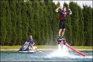 Matt Jackson, left, of Toledo Flyboarding, pilots a jet ski as Jeff Grashel, right, flexes his biceps to show off for his friends.