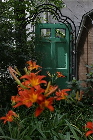 Ms. Carter paints doors and uses them to decorate her backyard garden. Pictured at front are orange Day Lilies.  