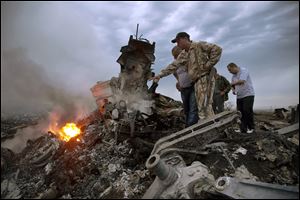 People inspect the crash site of a passenger plane near the village of Hrabove, Ukraine. 