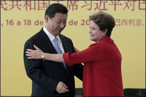 China's President Xi Jinping, left, and Brazil's President Dilma Rousseff, move to embrace after a signing ceremony Thursday at the Planalto Presidential Palace, in Brasilia, Brazil.