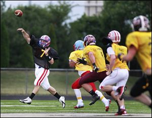 Saint Francis quarterback David Nees of the black team throws a pass while rushed by a group of gold team players.