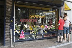 People look at flowers laid in memory of Willem Grootscholten, a victim of flight MH17, who worked for 12 years as a bouncer at the cannabis-selling cafe Andersom in Utrecht, Netherlands.