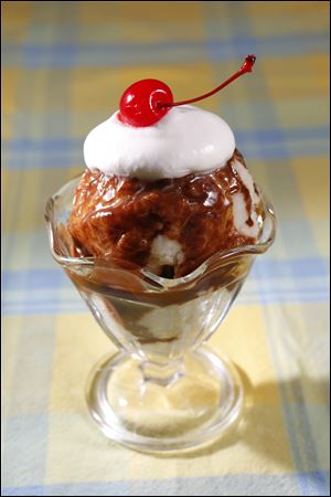 Hot fudge, whipped cream and a cherry is added to ice cream for a sundae.