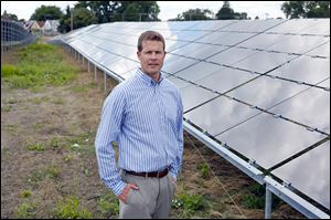 Jason Slatter, director of solar for Rudolph Libbe, stands in front of the companye's solar array project, one of the largest of its kind in this area, off of Spencer Road.