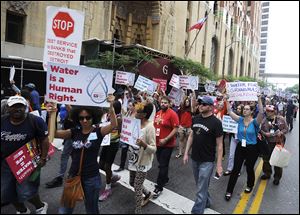 Protesters march over the controversial water shut-offs Friday, July 18, 2014, in Detroit, Mich.  