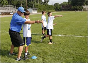 Siena Heights University coach and Detroit Lions Youth Football camp director Jim Hamilton works with campers on passing the football on Monday.